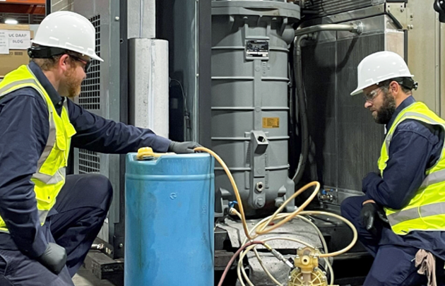 Two men in hard hats working on a machine